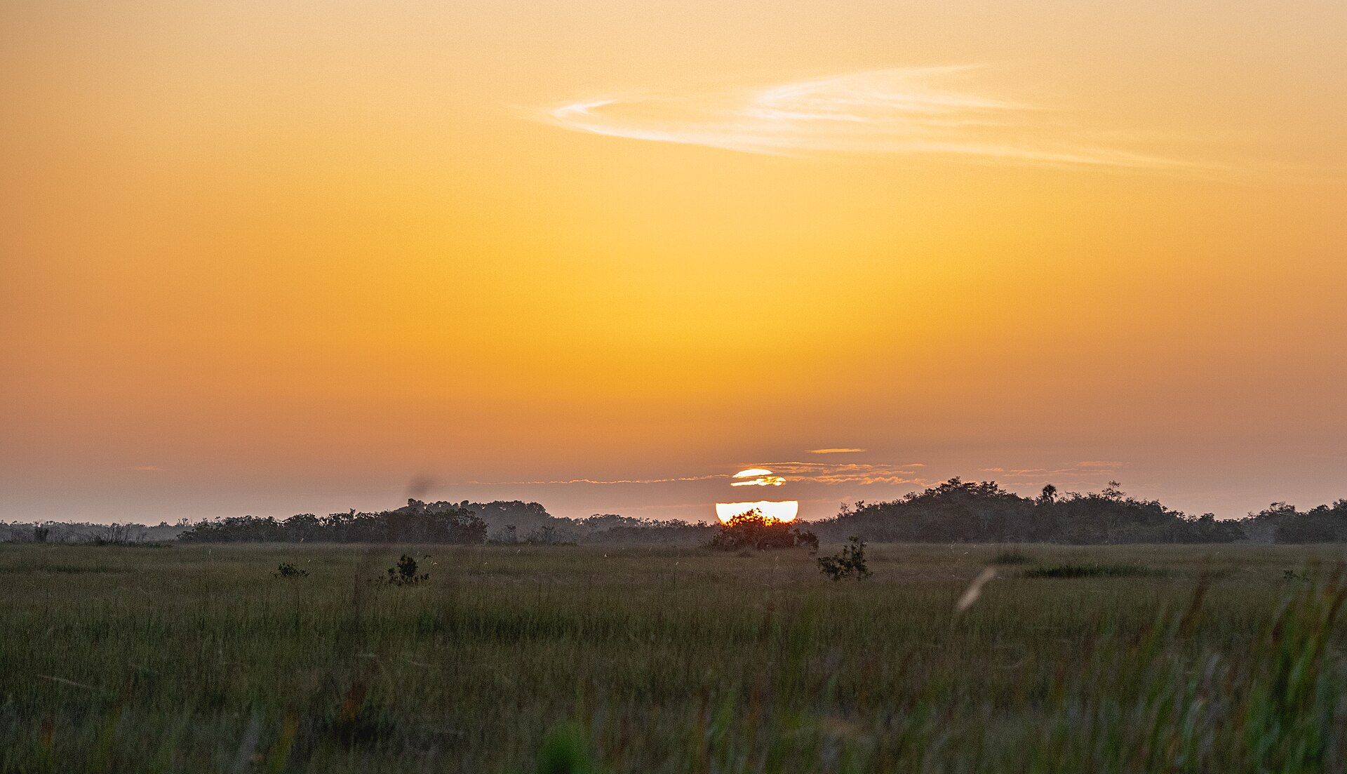 The sun setting over a wide sawgrass prairie and distant tree islands in Everglades National Park